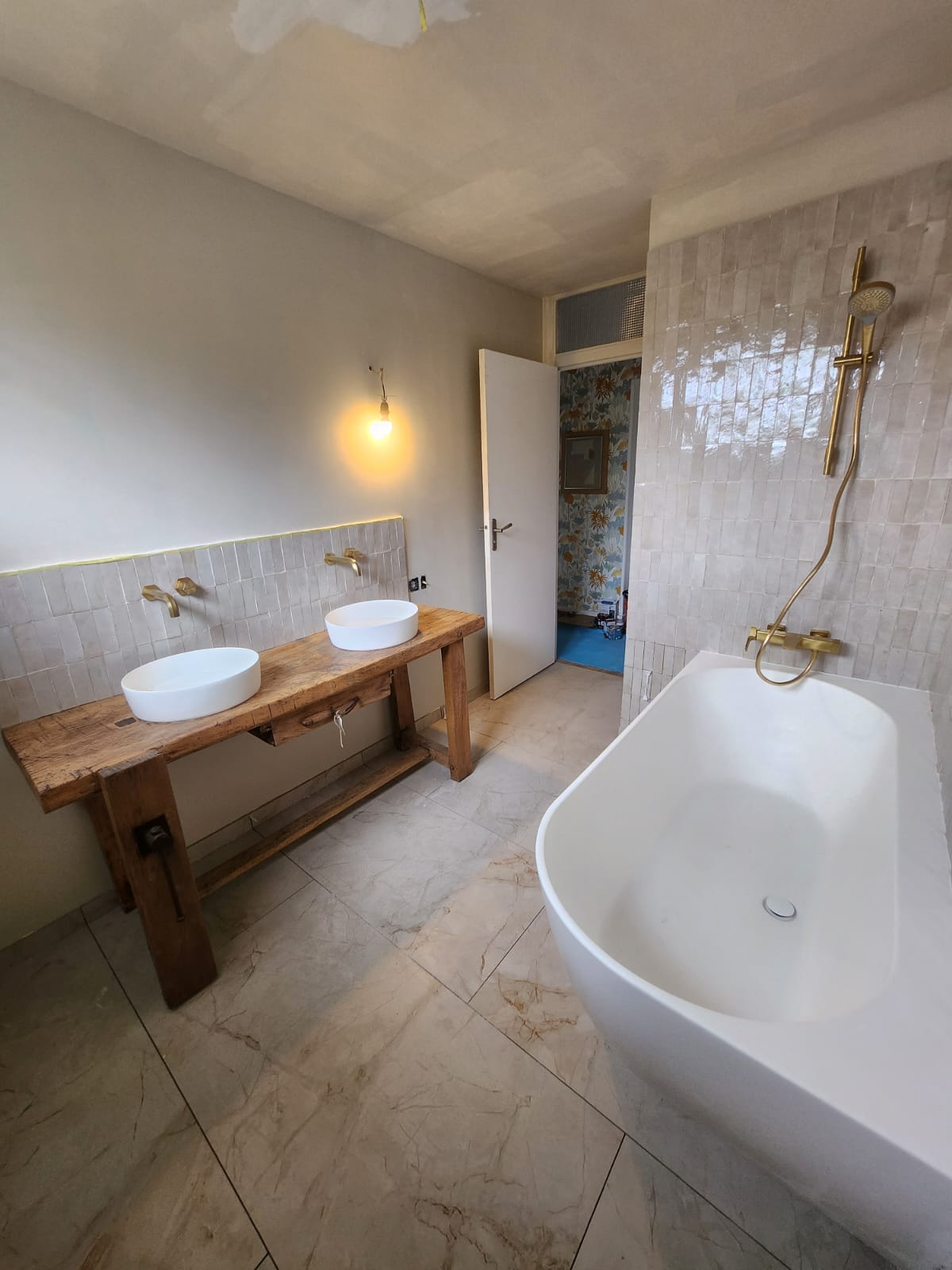 Salle de bain avec vasques sur meuble en bois brut et baignoire îlot.